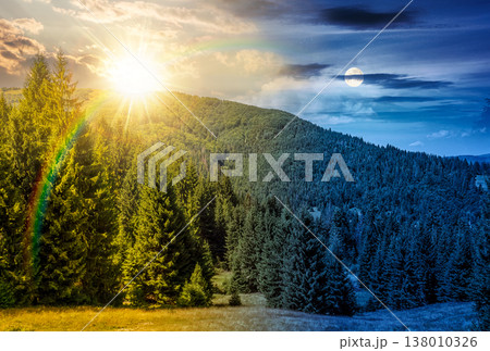 coniferous forest and green meadow at the foot of the mountain range scenery. day meet night. sun and moon over countryside summer landscape with cloudy sky at twilight. scenic alpine environment 138010326