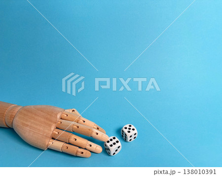 Wooden hand reaching for dice on a blue background during a tabletop game activity 138010391