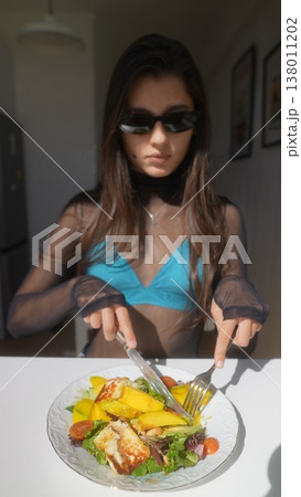 Stylish woman with sunglasses focusing on her meal during peaceful moment Stylish woman with sunglasses focusing on her meal during peaceful moment 138011202