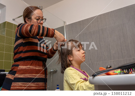 Woman creates neat hairstyle for child after washing before the start of day. Woman creates neat hairstyle for child after washing before the start of day. 138011212