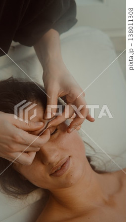 Gentle facial therapy. Softly massaging jaw and brow in peaceful setting Gentle facial therapy. Softly massaging jaw and brow in peaceful setting 138011308