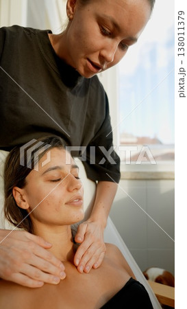 Woman enjoying tranquil massage under warm glow and soft linens 138011379