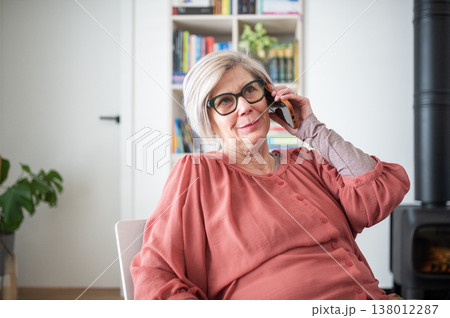 Older woman talking on phone while working from home during retirement. Older woman talking on phone while working from home during retirement. 138012287