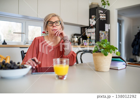 Senior woman working on tablet at home office during retirement. Senior woman working on tablet at home office during retirement. 138012292