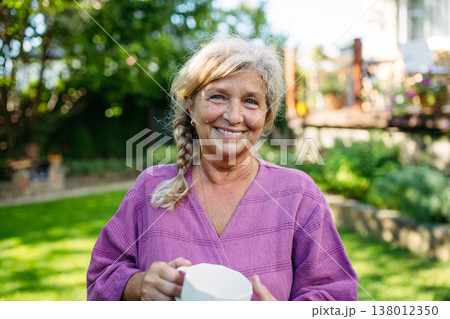 Quiet morning in garden for older woman. Self ritual with coffee. 138012350