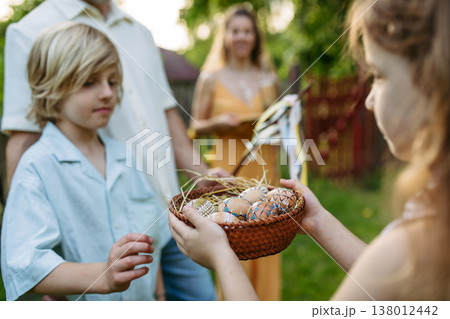 Girl giving decorated Easter eggs to boy after Easter Monday tradition. Girl giving decorated Easter eggs to boy after Easter Monday tradition. 138012442