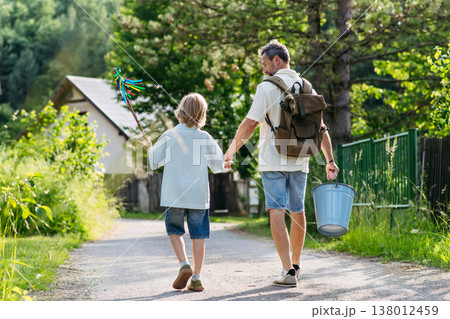 Father and son heading to Easter Monday visits with whip and water bucket. 138012459