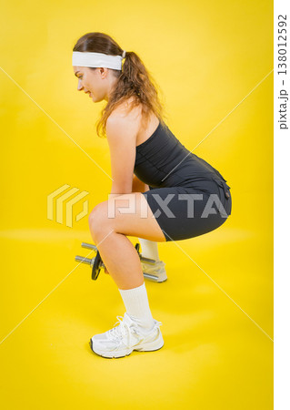 Woman squatting with dumbbells doing strength training Woman squatting with dumbbells doing strength training 138012592