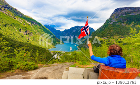 Tourist over Geirangerfjord holds norwegian flag Tourist over Geirangerfjord holds norwegian flag 138012763
