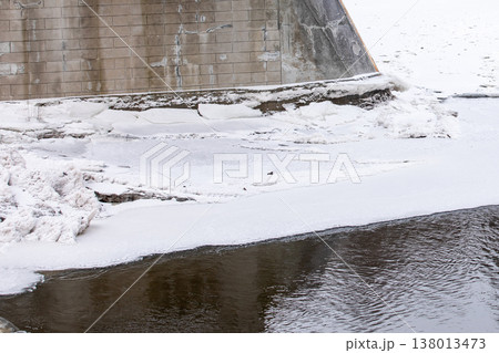 Frozen River Ice Along Concrete Bridge Foundation In Winter Frozen River Ice Along Concrete Bridge Foundation In Winter 138013473
