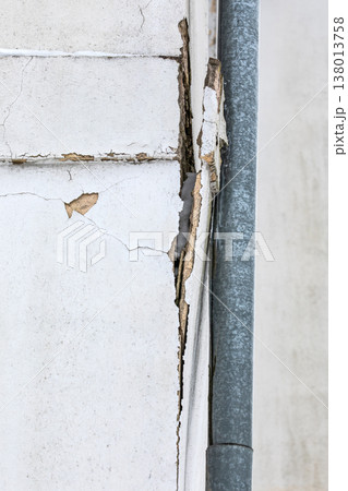 Cracked Exterior Wall With Peeling Plaster Beside Metal Drainpipe 138013758