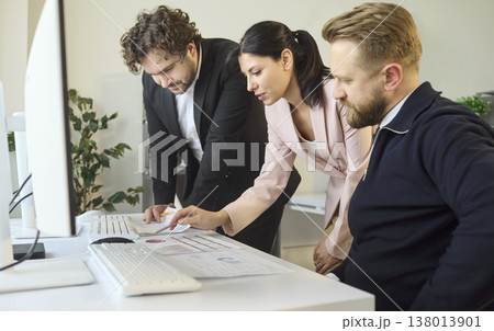 Colleagues reviewing analytics reports together at modern workplace desks Colleagues reviewing analytics reports together at modern workplace desks 138013901