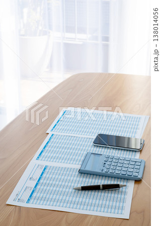 机の上のローン計算シートと電卓とスマホ 138014056