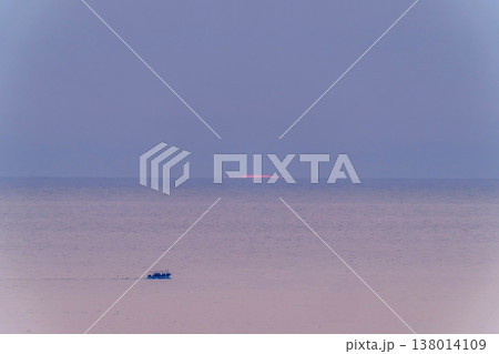 静寂な黄昏の海をゆく漁船と水平線に沈む夕日 静寂な黄昏の海をゆく漁船と水平線に沈む夕日 138014109