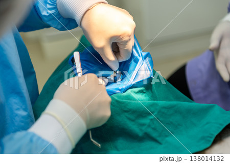Dentist performing dental procedure with tools gloves and protective cover focusing on oral care hygiene treatment precision and professional clinical environment 138014132