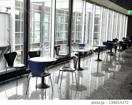 The interior of an airport terminal with panoramic windows and a seating area 138014272