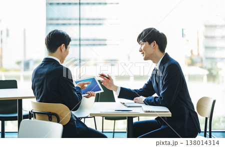 対面で打ち合わせをする若いビジネスマン 対面で打ち合わせをする若いビジネスマン 138014314