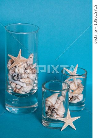 Assorted seashells and starfishes in glass vases on a blue background 138015715