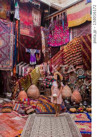 a beautiful girl in dress in a traditional turkish interior with many carpets on the wall 138016172