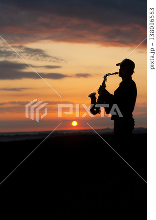 a boy musician plays the saxophone against the background of a beautiful sunset a boy musician plays the saxophone against the background of a beautiful sunset 138016583