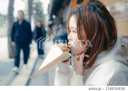 観光地で焼きたてパンを食べ歩きする20代女性 138016836