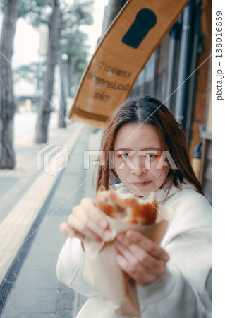 観光地で焼きたてパンを食べ歩きする20代女性 観光地で焼きたてパンを食べ歩きする20代女性 138016839