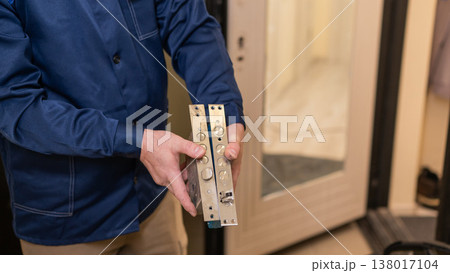 The technician changes the lock on the front door. 138017104