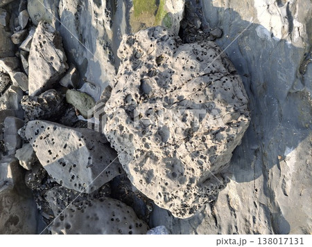 Natural coastal rock forms with textured and weathered boulders by the shore offer a striking look at how the sea shapes stone over time 138017131