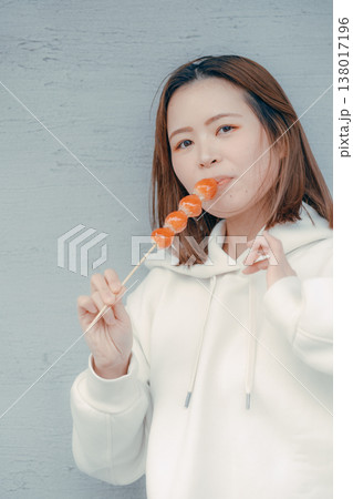 観光地でいちご飴を楽しむ20代女性のポートレート 観光地でいちご飴を楽しむ20代女性のポートレート 138017196