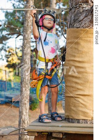 Child Wearing Safety Gear on Outdoor Adventure Park Course 138017241