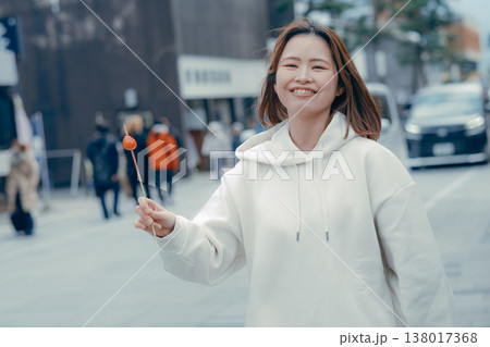 観光地で食べ歩きを楽しむ20代女性の街歩きシーン 観光地で食べ歩きを楽しむ20代女性の街歩きシーン 138017368