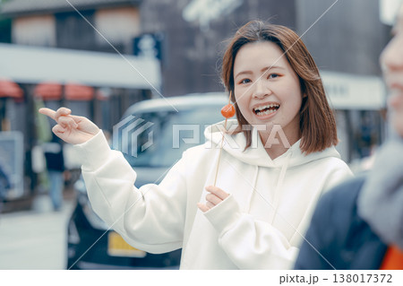 観光地で食べ歩きを楽しむ20代女性の街歩きシーン 観光地で食べ歩きを楽しむ20代女性の街歩きシーン 138017372