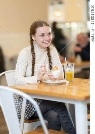 Food court teen girl visitor sits near table, eating ice cream in chain cafe shop 138017616