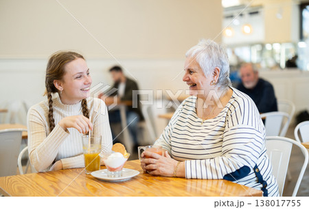 Grandmother and teenage girl sitting at table in cafe. Grandmother and teenage girl sitting at table in cafe. 138017755