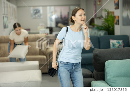 Womans eyes scan room furniture store, searching for perfect item to complete living space Womans eyes scan room furniture store, searching for perfect item to complete living space 138017856