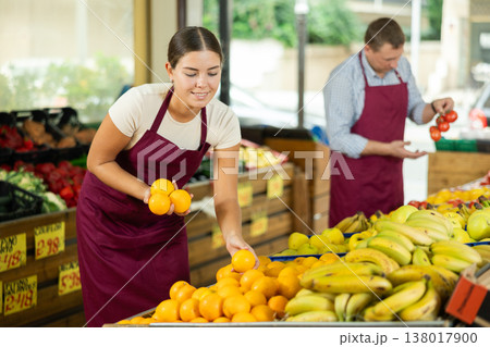Girl seller was distracted for minute and stands smiling with ripe oranges in hands 138017900