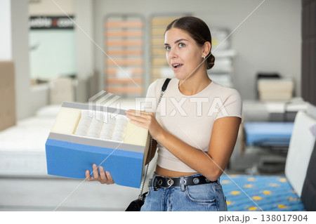 Girl chooses mattress filling in furniture store Girl chooses mattress filling in furniture store 138017904