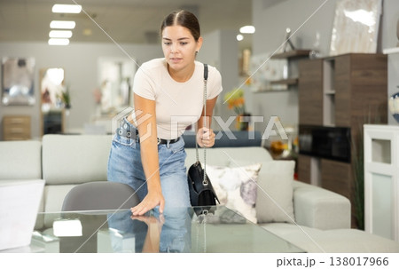 Young girl choosing dining table in furniture store 138017966