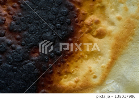 Macro view of a scorched, rough surface, revealing a gradient of black charring transitioning to warm golden-brown and cream tones Macro view of a scorched, rough surface, revealing a gradient of black charring transitioning to warm golden-brown and cream tones 138017986