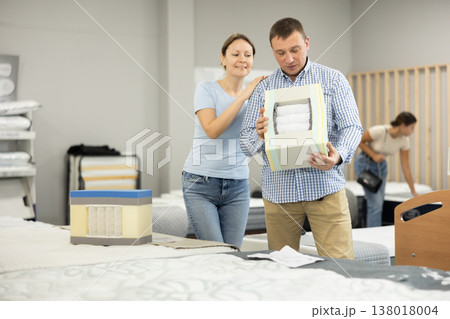 Married couple chooses and discusses mattress filling in furniture store Married couple chooses and discusses mattress filling in furniture store 138018004