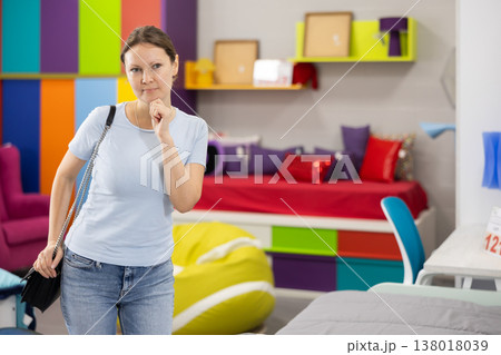Interested woman choosing functional furniture for home in shop 138018039