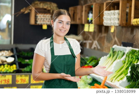 Positive and friendly store girl employee stands with arms crossed on chest and waits for customers 138018099