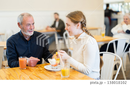 Teenage girl has fun with her elderly parents in cafe 138018102
