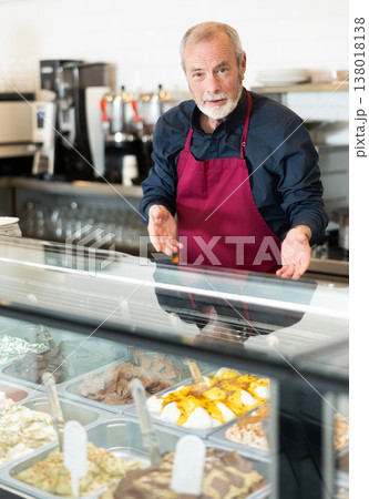 Elderly man working in ice cream parlor Elderly man working in ice cream parlor 138018138