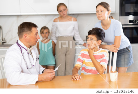 Family physician consults boy child with sore throat from large family at home 138018146