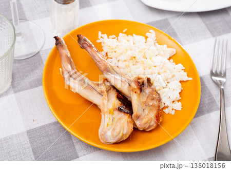 Lunch is served on plate - baked pieces of young rabbit with side dish boiled rice. 138018156