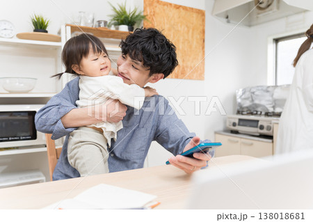 在宅ワーク中、ぐずる子供を優しくあやす若い父親 在宅ワーク中、ぐずる子供を優しくあやす若い父親 138018681