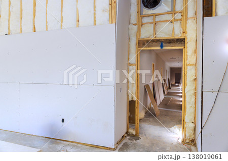 Drywall is being installed after installing insulation in hallway of new building. 138019061
