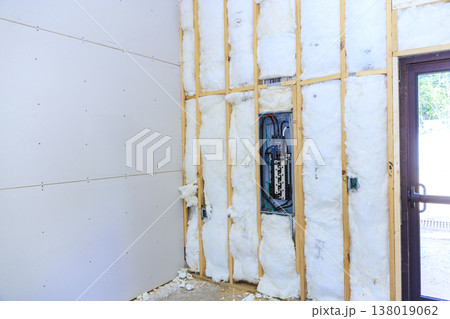 Workers are installing insulation setting up near electrical panel in house under renovation 138019062