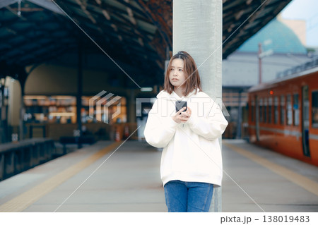 駅のホームでスマホを操作する女性 駅のホームでスマホを操作する女性 138019483